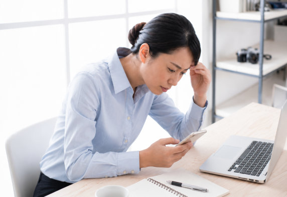 スマートフォンを見続けることで首や肩へ負担がかかり頭痛につながる女性
